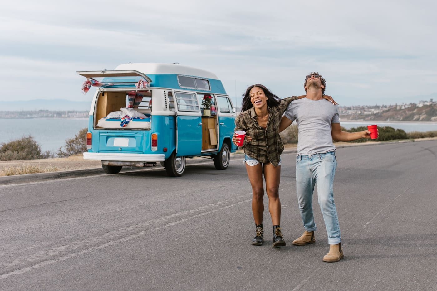 Young couple enjoying a carefree road trip by the seaside with a vintage van.