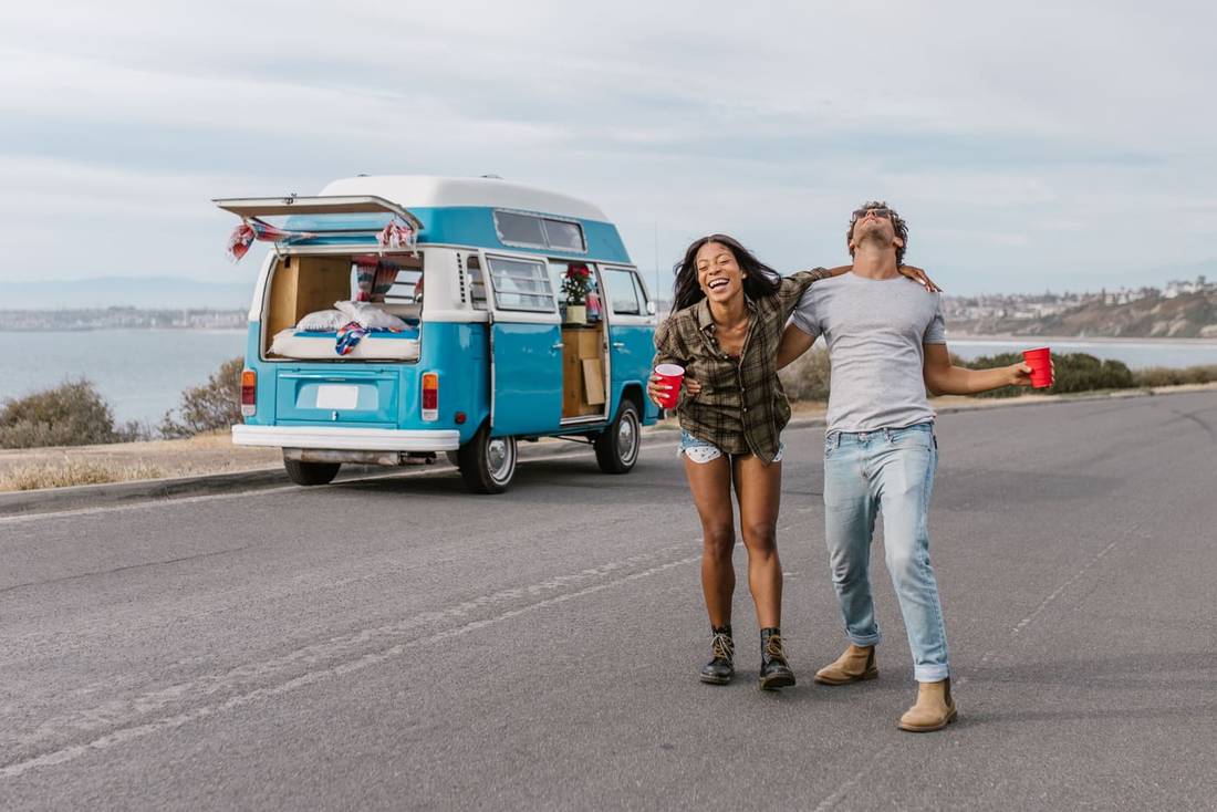 Young couple enjoying a carefree road trip by the seaside with a vintage van.