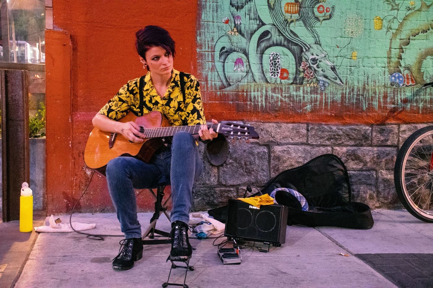 A street musician playing guitar by a graffiti-covered wall, adding urban charm.