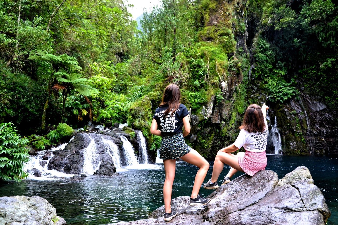 Two women enjoying a breathtaking view of a waterfall surrounded by lush greenery.